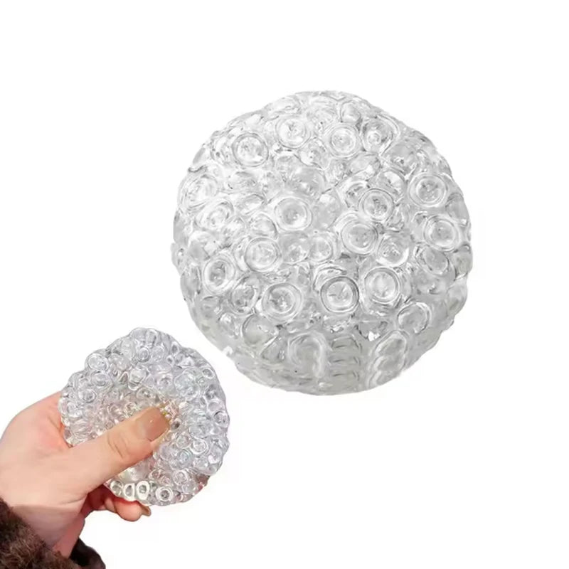 A clear, spherical stress relief ball made of many small, tightly packed, squishy bubbles.