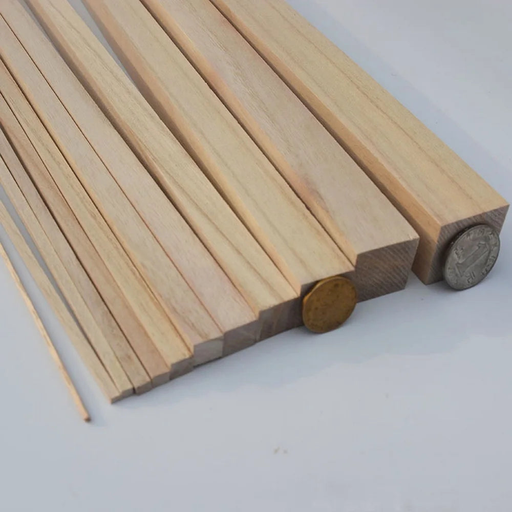 A collection of light-colored natural wood strips laid out, showing various lengths and thicknesses for DIY crafts.