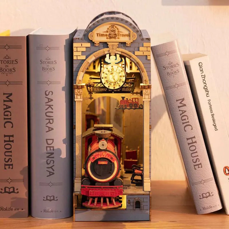 A miniature dollhouse kit featuring a train model displayed in a wooden frame with glass and lighting.