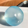 A translucent light blue squeezy ball resting on a white surface.