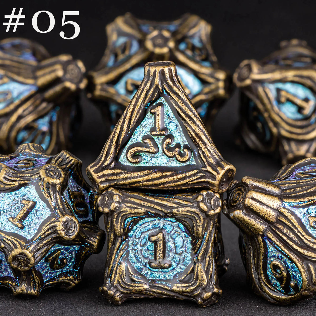 A set of five polyhedral metal dice in gold and blue tones displayed against a dark background.
