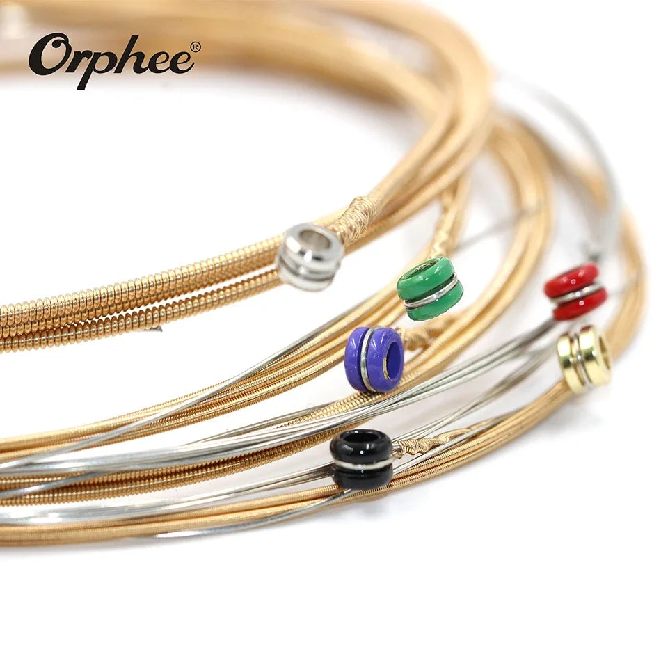 A close-up of Orphée acoustic guitar strings in bronze and silver, showing various gauges and ball ends.