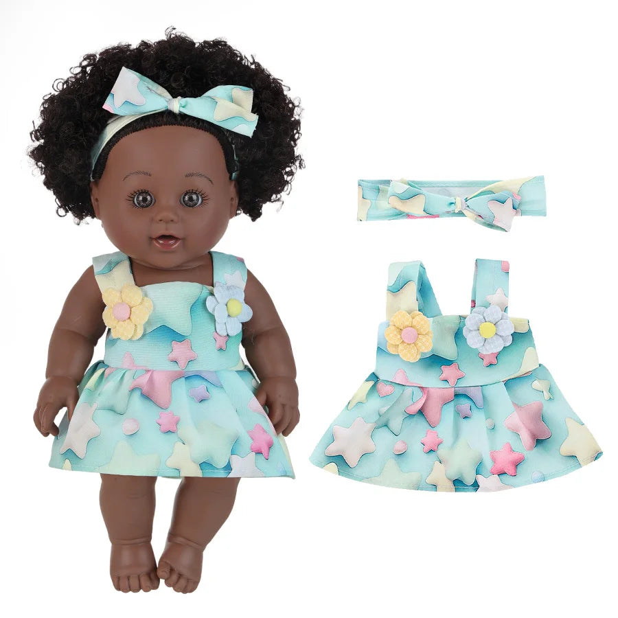 A realistic African American baby doll wearing a light blue dress with star and floral accents.