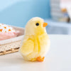 A fluffy yellow chick plush toy with orange beak sitting on a white surface.