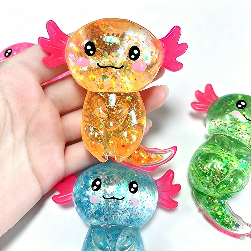 A hand holds a glitter axolotl squishy toy in orange and blue colors.