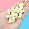 A hand holds a pack of ten colorful, striped polymer clay marshmallow charms for DIY crafts.
