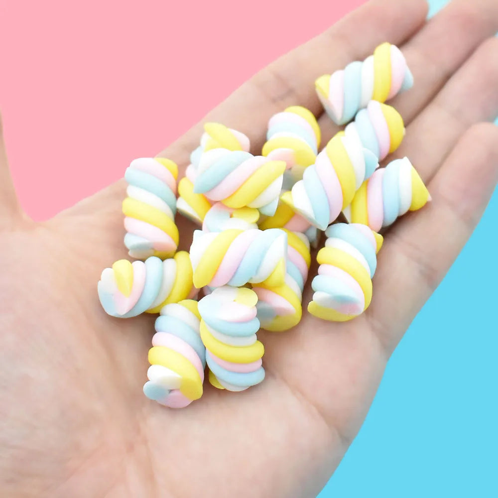 A hand holds a pack of ten colorful, striped polymer clay marshmallow charms for DIY crafts.
