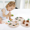 A young girl is interacting with a wooden learning set featuring various animals and plants for life cycle education.