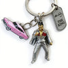 A keychain featuring a figurine of Michael Jackson in a suit and a pink car, attached to a metal buckle.