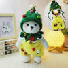A fluffy green Christmas elf plush toy wearing a yellow dress and a green hat.