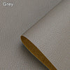 A close-up of a grey leather material with a brown edge showing a self-adhesive repair patch.