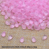 Pink water drop glass beads for jewelry making laid out on a woven fabric