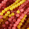 A close-up of colorful glass round beads in shades of yellow and pink strung on a thin wire.