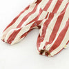 A close-up of a striped baby romper in beige and terracotta tones with a pocket detail.