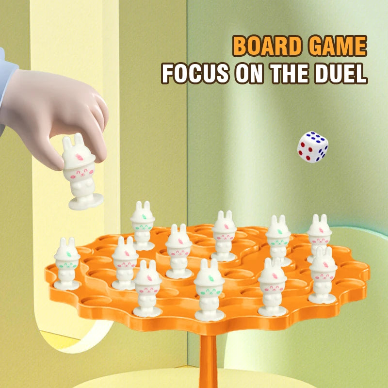 A board game setup featuring small white frog figures on an orange tree, with a hand reaching toward the game.