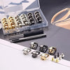 A collection of vintage metal D-ring buckle clips in gold and silver tones displayed in an open plastic box.