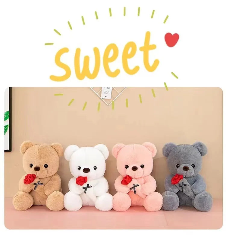 A row of four plush teddy bears, including a brown, white, pink, and gray bear, each holding a red rose.