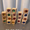 A collection of wooden building blocks with various colored acrylic gemstones arranged in a row.