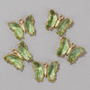 A set of green crystal butterfly charm beads used for jewelry making.