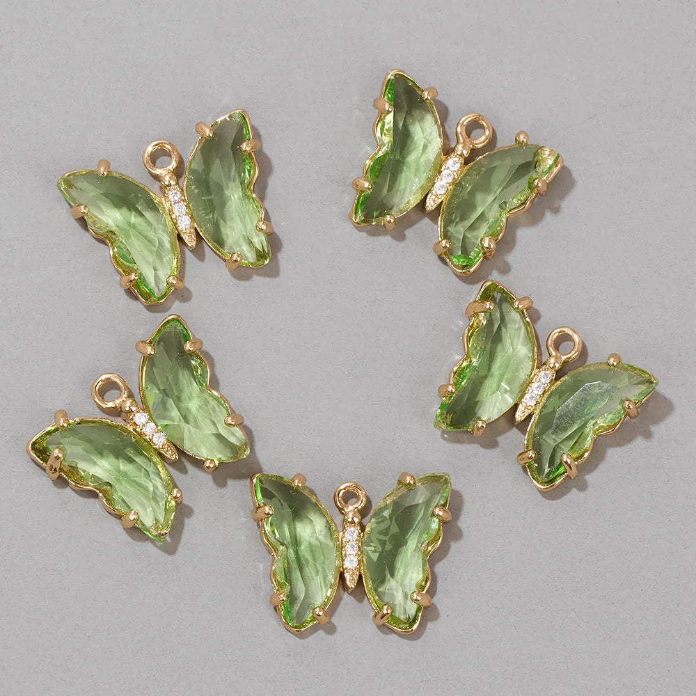 A set of green crystal butterfly charm beads used for jewelry making.