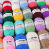 A collection of various colored yarn skeins including pink, red, green, yellow, purple, and white wool for crafting.