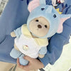 A light blue plush teddy bear wearing a yellow collar and a light blue outfit.