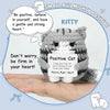 A handmade crochet cat figurine with gray and white stripes is shown resting on a person's hand.
