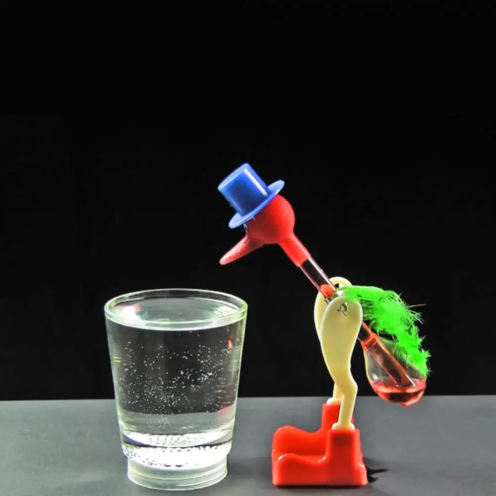 A red and blue drinking bird toy with a green feather, resting on a glass.