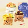 A set of crochet animals made from yarn, including a small potted animal and a larger stuffed animal, next to a purple kit ba