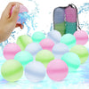 A hand is squeezing a pink silicone water balloon, with many colorful silicone water balloons scattered on a blue surface.