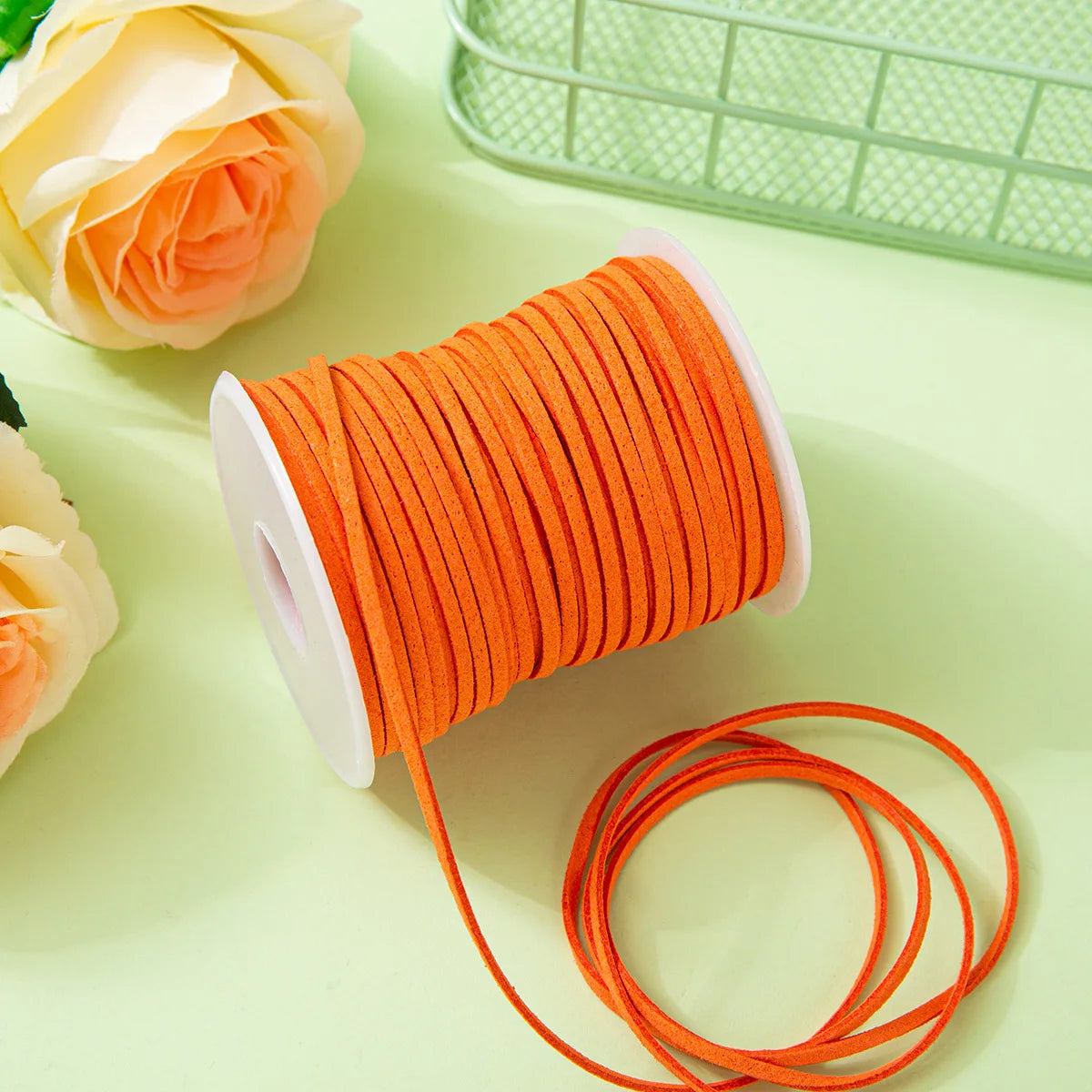 Orange braided ribbon roll for crafting and gift wrapping next to a light green basket.