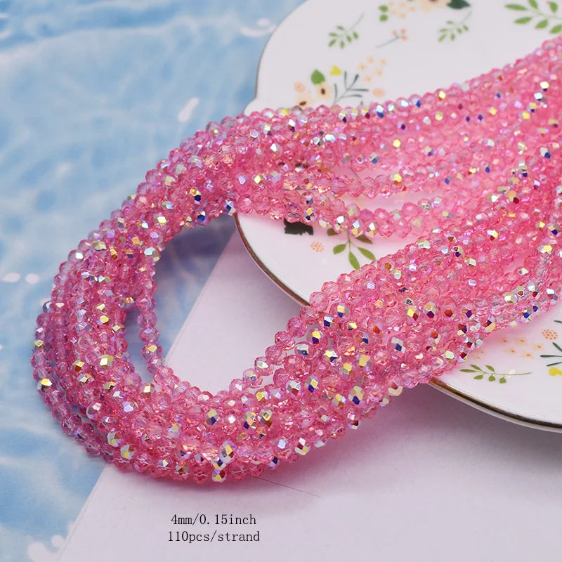 Pink faceted crystal rondelle beads for jewelry making displayed on a white surface.