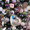 A close-up view of various iridescent and colored acrylic beads, including bow shapes and flowers, for DIY jewelry making.