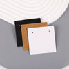 Three square kraft jewelry display cards in black, brown, and white are displayed on a gray surface.