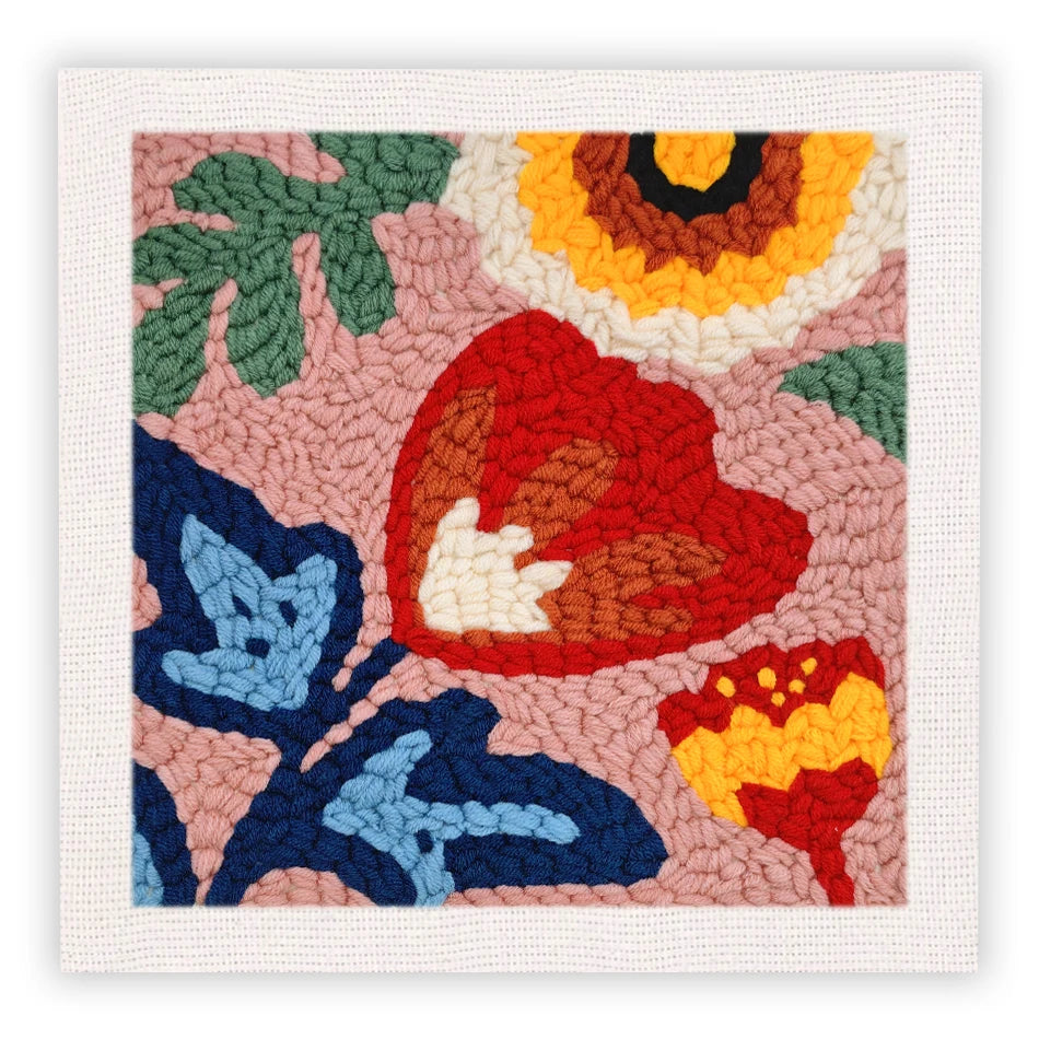 Punch needle embroidery kit featuring a floral pattern with shades of orange, red, green, and pink on a beige fabric.