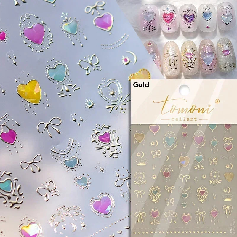 A collection of gold and iridescent nail art stickers featuring hearts, butterflies, and decorative elements on a light backg