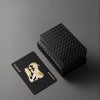 A black gift box containing premium frosted poker playing cards with gold foil designs.
