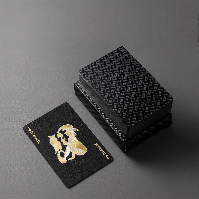 A black gift box containing premium frosted poker playing cards with gold foil designs.