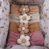 A collection of pink, beige, and mauve floral elastic baby headbands for newborn girls.