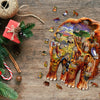 A wooden jigsaw puzzle depicting an elephant in a jungle scene is scattered on a wooden surface with festive greenery and nat