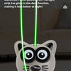 A hand holds a white cat toy with black markings, featuring glowing green rope lights.