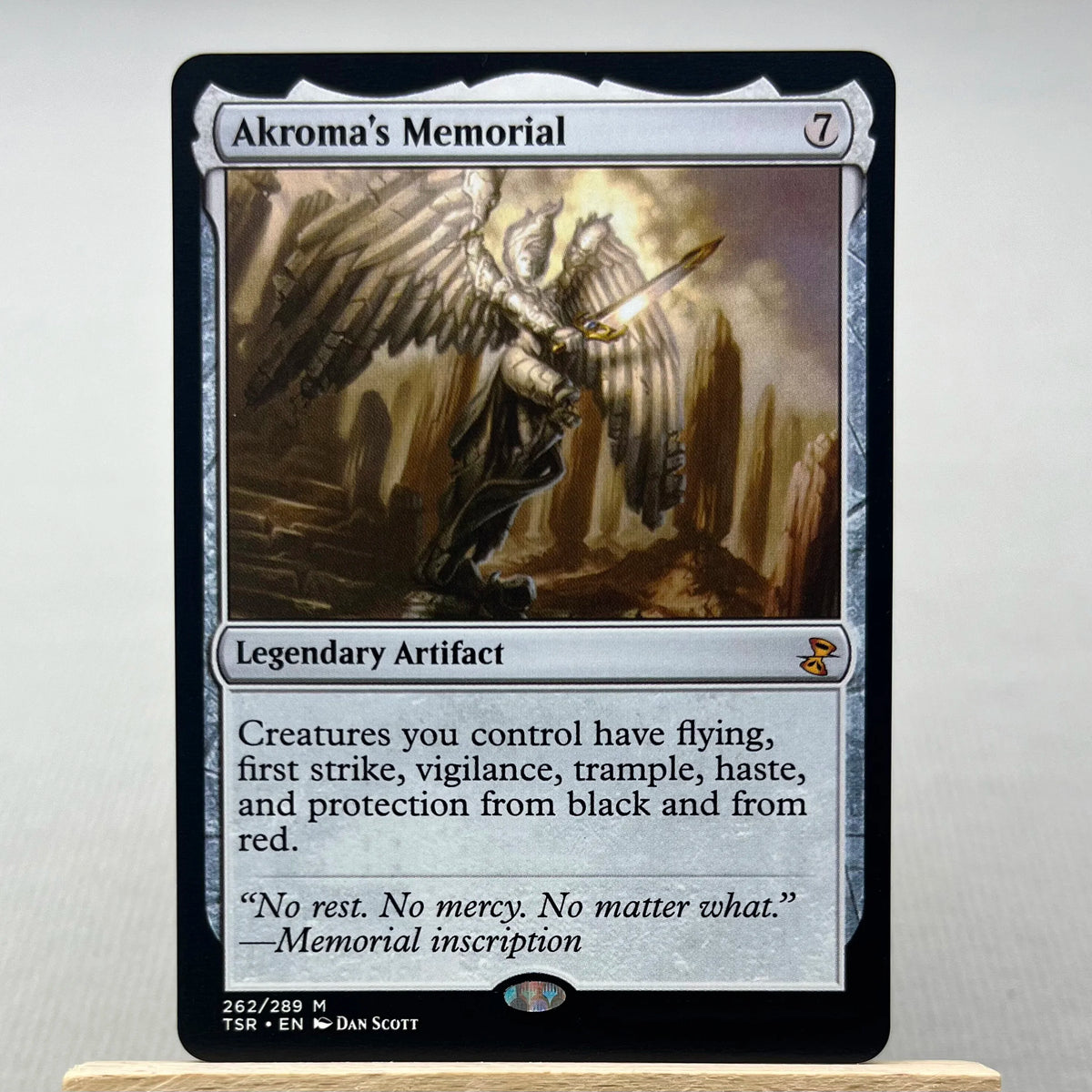 A Magic: The Gathering card named Akroma's Memorial featuring a winged figure and text describing creatures with flying, firs