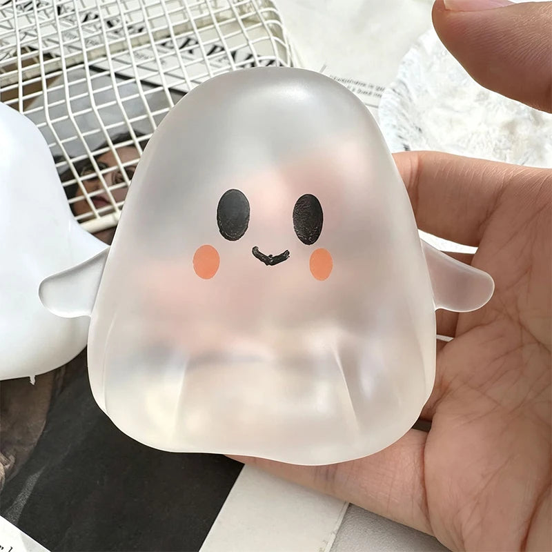 A translucent, squishy ghost-shaped toy with black eyes and orange cheeks is held in a hand.
