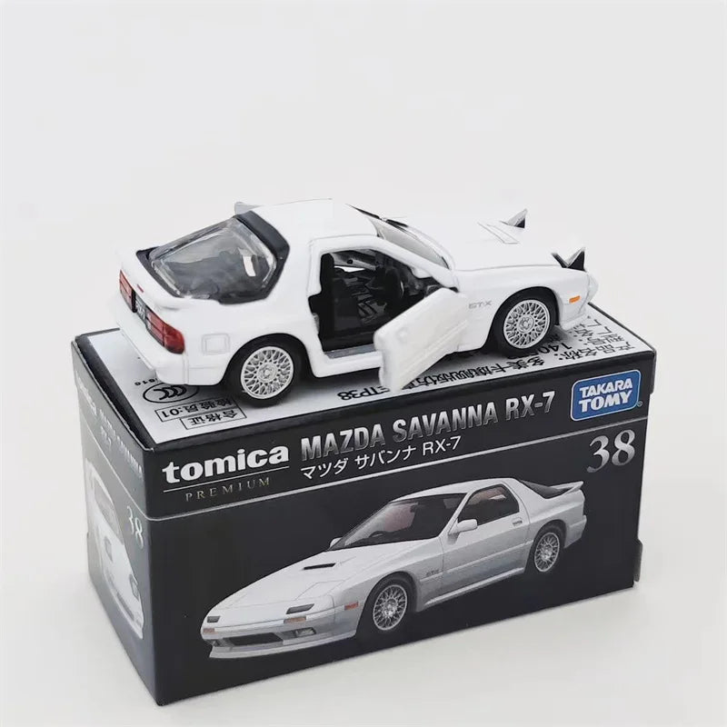 A white Mazda Savanna RX-7 die-cast model by Tomica featuring a black interior and displayed in its packaging.