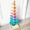 A wooden rainbow ball track toy featuring colorful, layered blocks arranged vertically.