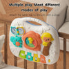 A white musical baby piano playmat with a light-up keyboard and hanging toys attached to a crib rail.