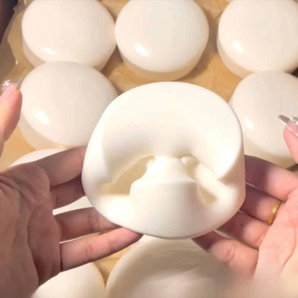 A hand holds a white yogurt cake squishy stress relief toy against a background of similar products.
