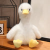 A realistic white call duck plush toy with a yellow beak sitting on a wooden surface.