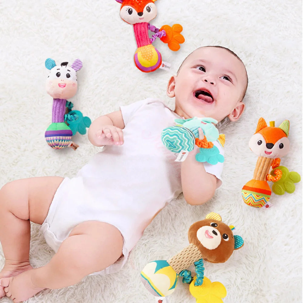 A baby is holding a soft plush rattle toy set featuring crinkle and squeak sounds.