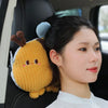A woman is seated in a car, holding an adorable yellow plush animal lumbar support pillow with brown ears.